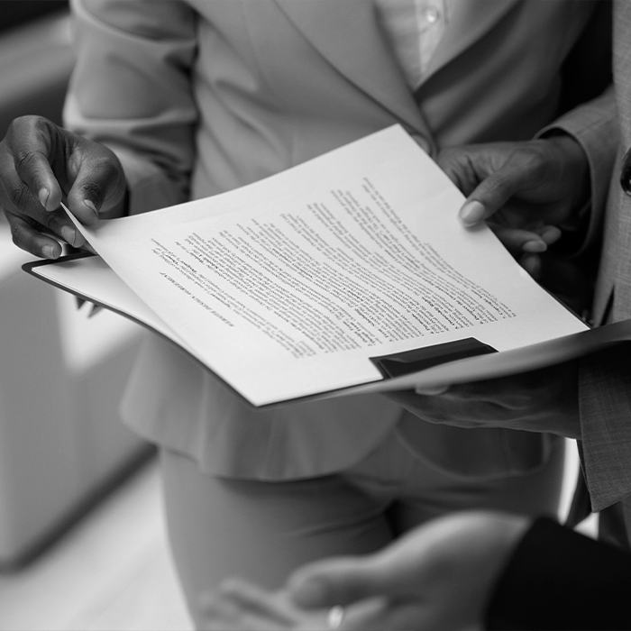 Foto em preto e branco mostra três pessoas analisando documento representando os enunciados do CJF